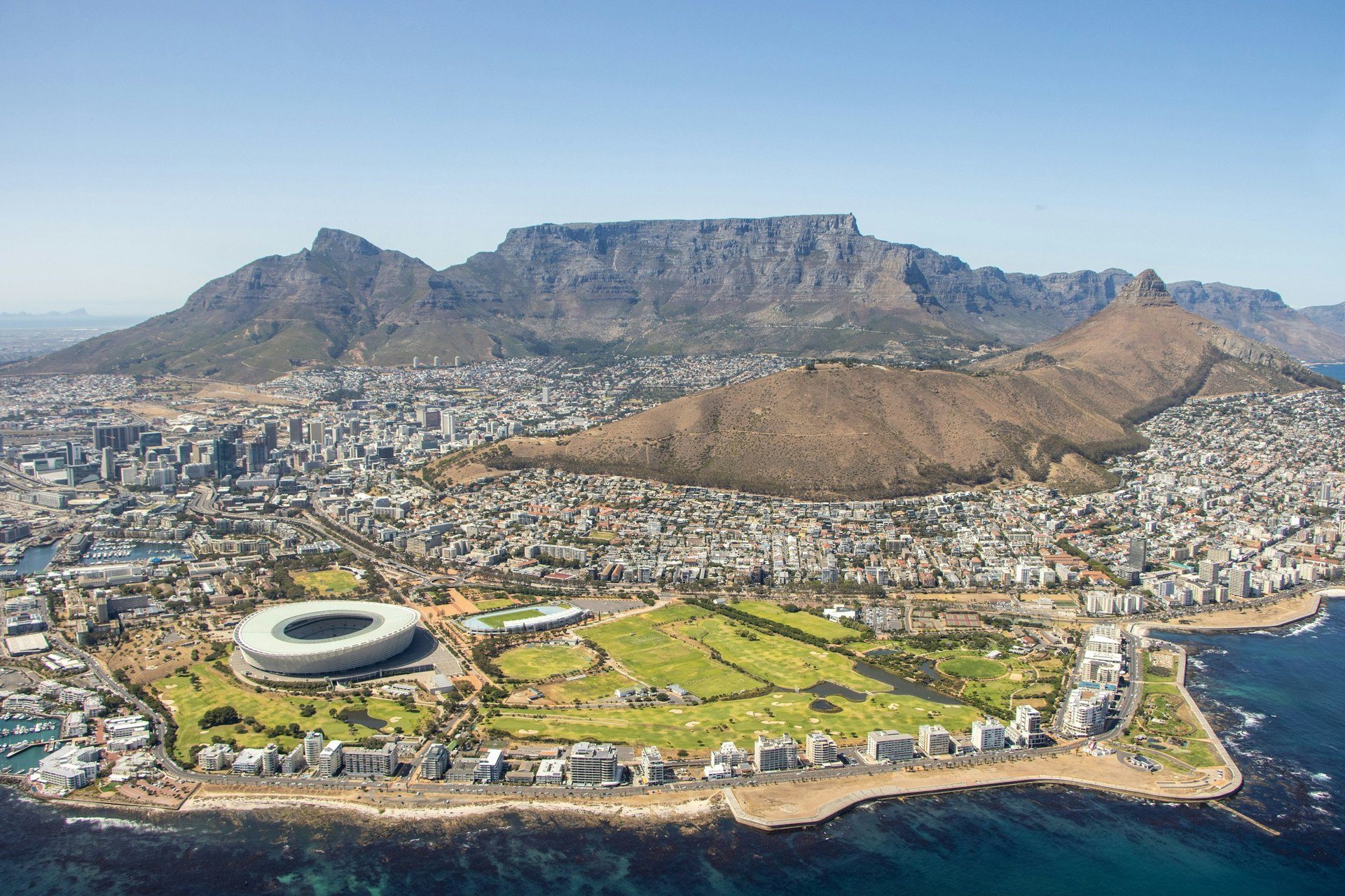 Breathtaking aerial view of Cape Town's city bowl framed by Table Mountain, Lion's Head and Signal Hill, with the Atlantic coastline beyond