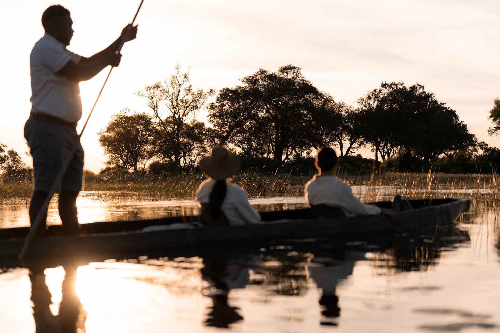 A traditional mokoro canoe glides through the Okavango Delta at golden hour