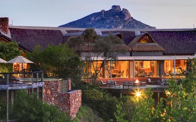 Botlierskop tented lodge at dusk beneath its rocky peak on the Garden Route