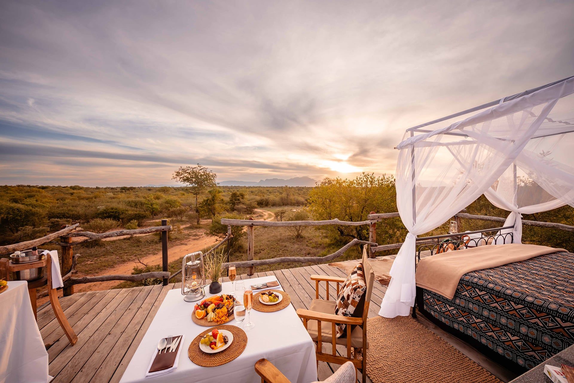 Couple watching sunset from a luxury safari lodge deck overlooking the African bush