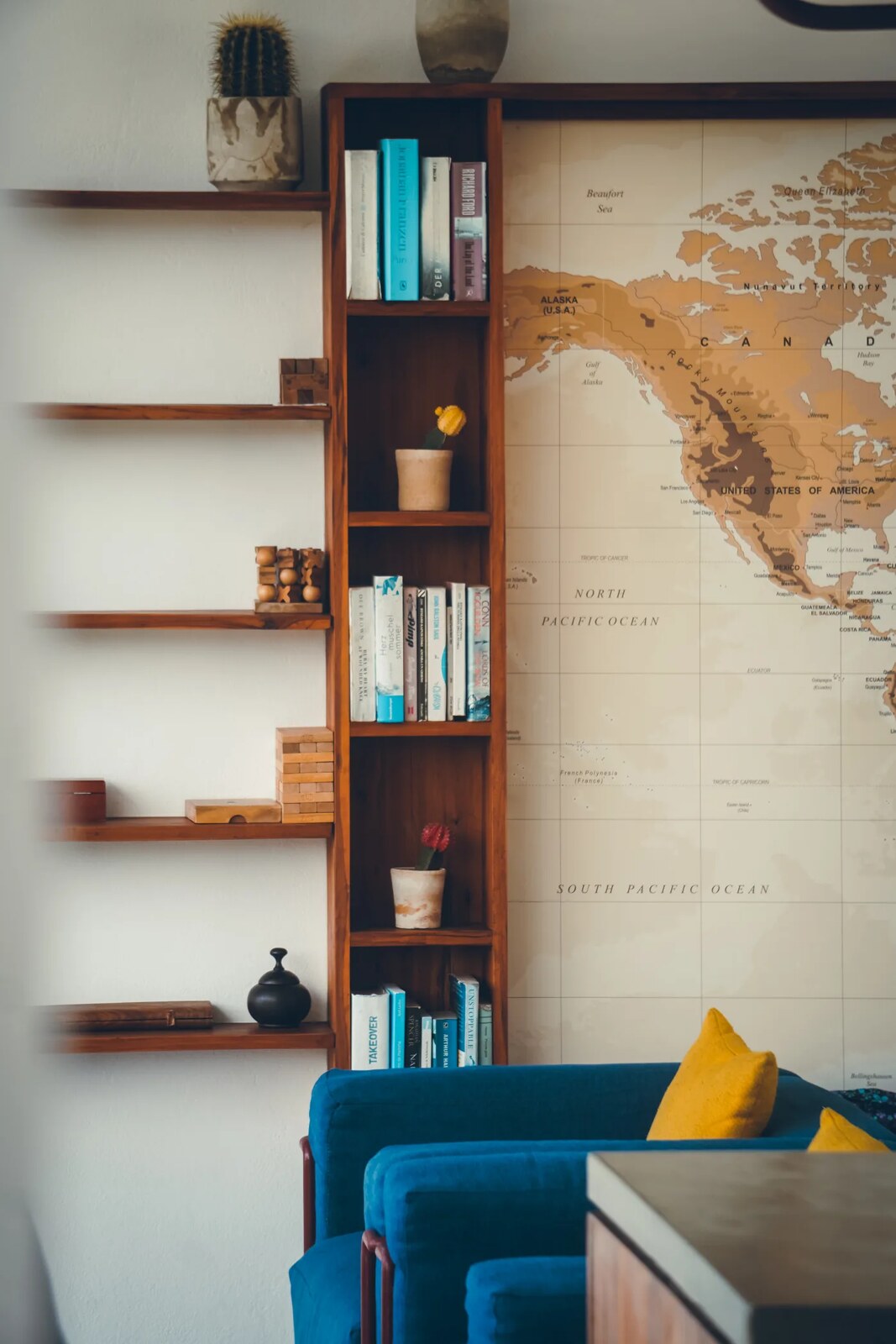 Styled living space with bookshelf, framed map and blue sofa at Duna Sonâmbula villa, Tofo, Mozambique