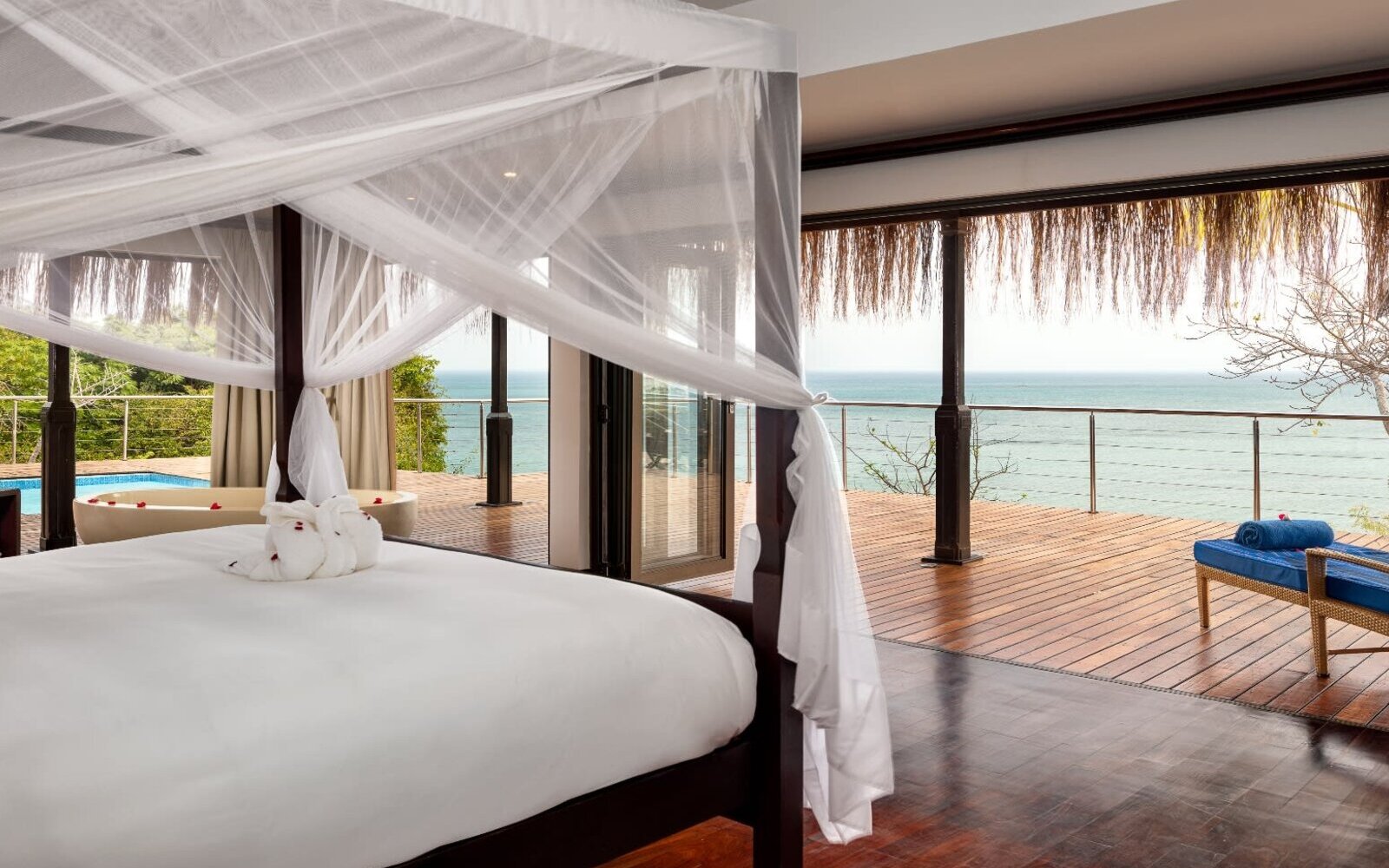 A four-poster canopy bed in a beach villa opening onto an ocean-view deck on Bazaruto Island