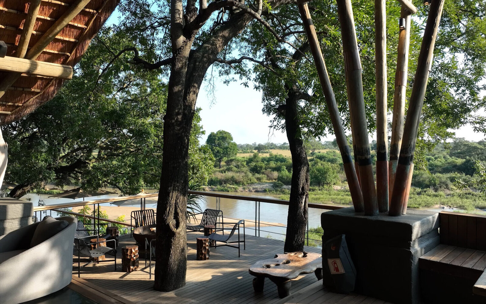A riverfront lounge deck at Singita Boulders Lodge overlooking the dry riverbed and bush beyond