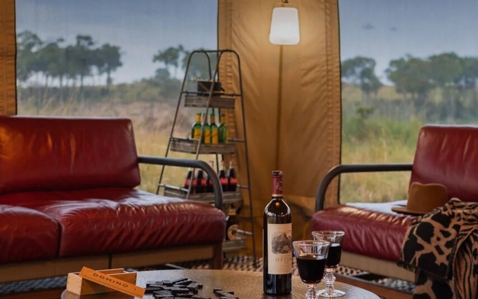 A suite lounge with a bottle of wine and armchairs looking straight out over the Mara plains at Angama