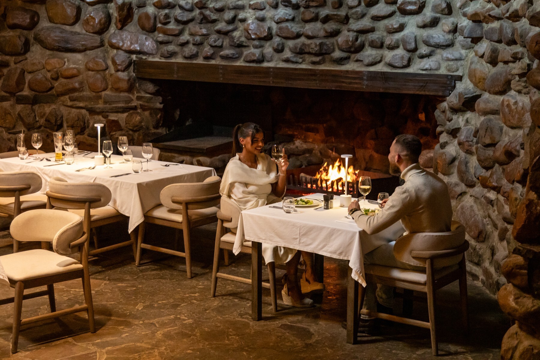 Guests dining beside the stone fireplace in the main lodge at Inverdoorn