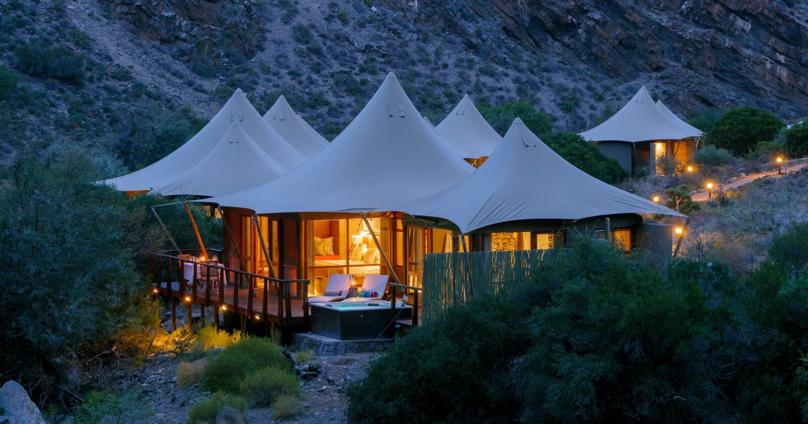 Dwyka Tented Lodge suites lit at dusk within a dry Karoo ravine at Sanbona