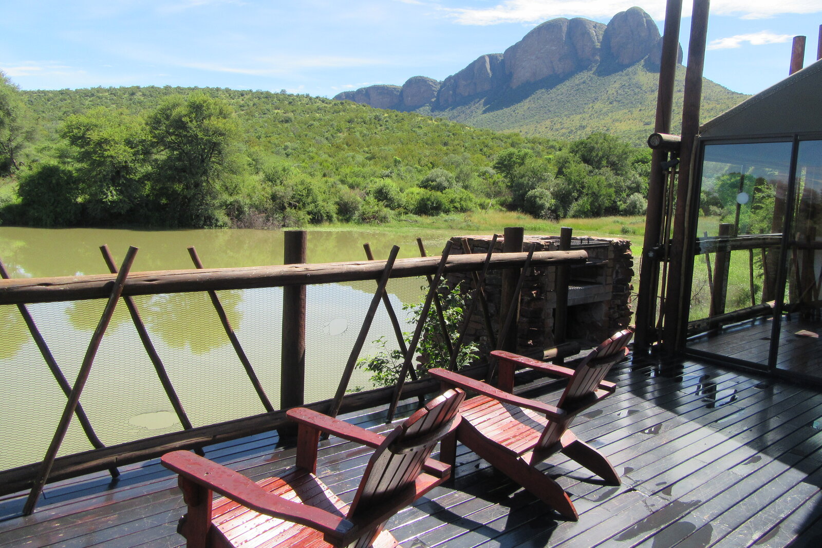 A camp deck with chairs overlooking water and wilderness in Zinave National Park, Mozambique
