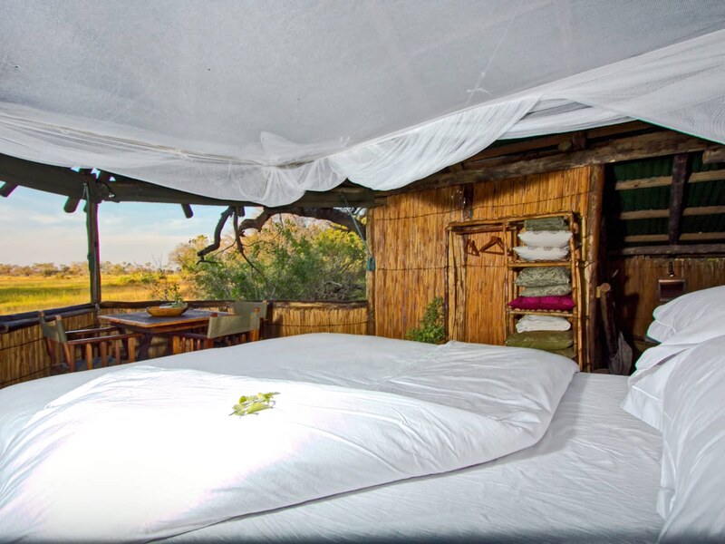 Reed-and-canvas guest tent interior at Delta Camp with a mosquito-netted double bed