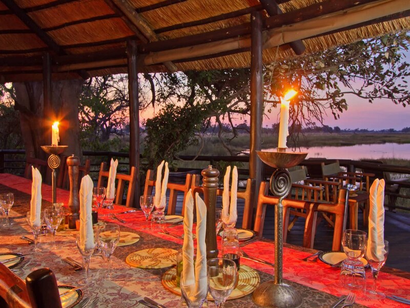 Candlelit riverside dining deck at Delta Camp at dusk