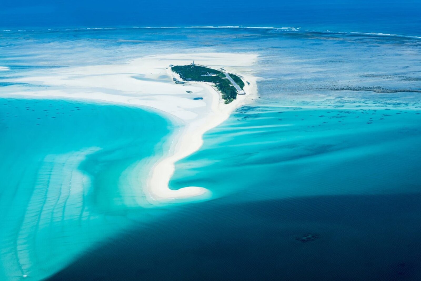 A turquoise sandbank curving through deep-blue Indian Ocean water