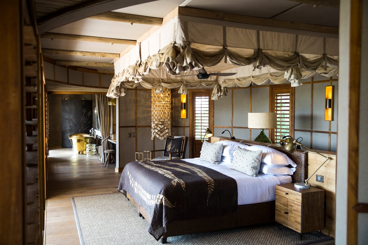 A luxurious glass-and-canvas suite interior with four-poster bed and freestanding bath at Mombo Camp, Okavango Delta