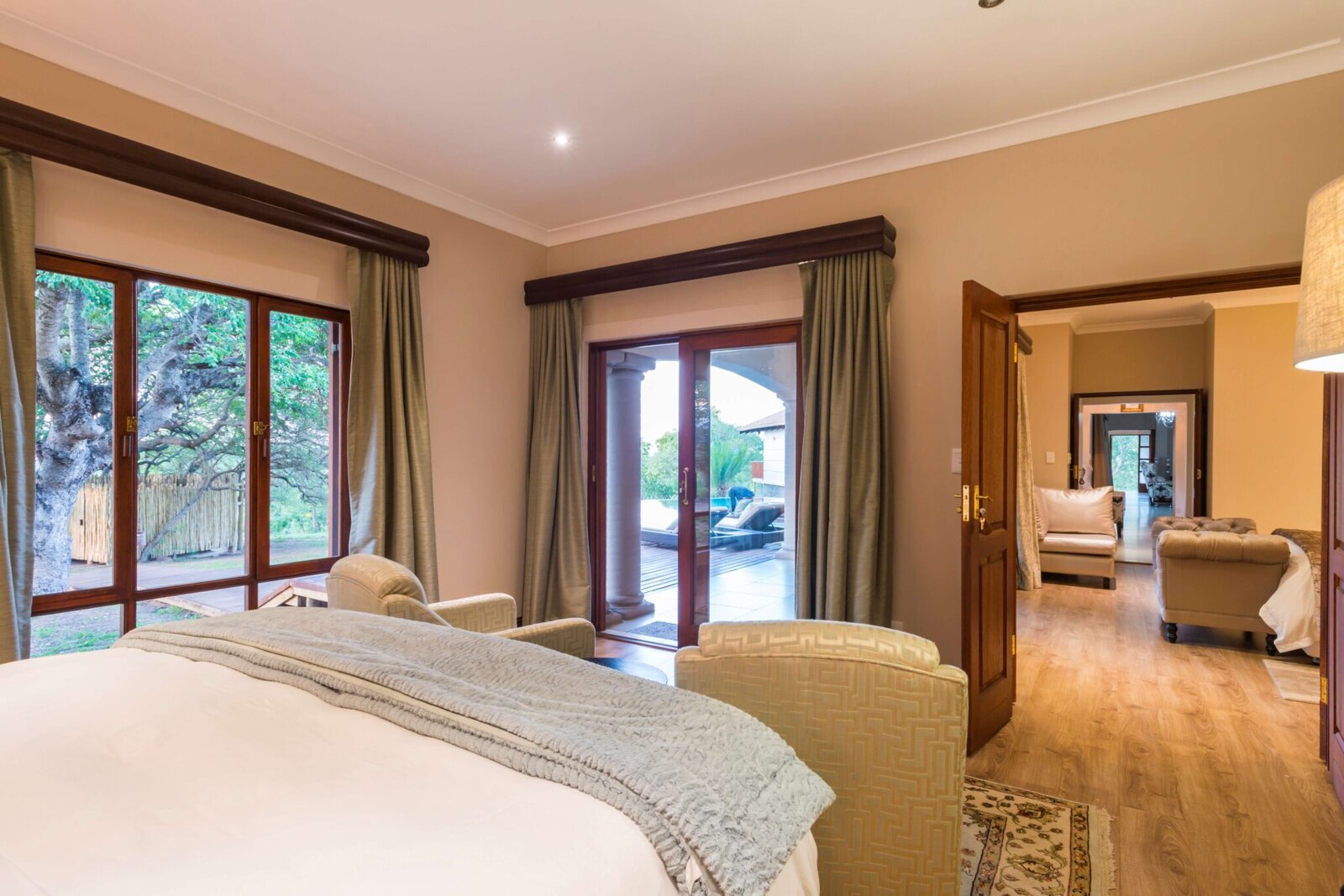 A suite bedroom with glass doors to the bush and a lounge beyond at AM Lodge, Klaserie