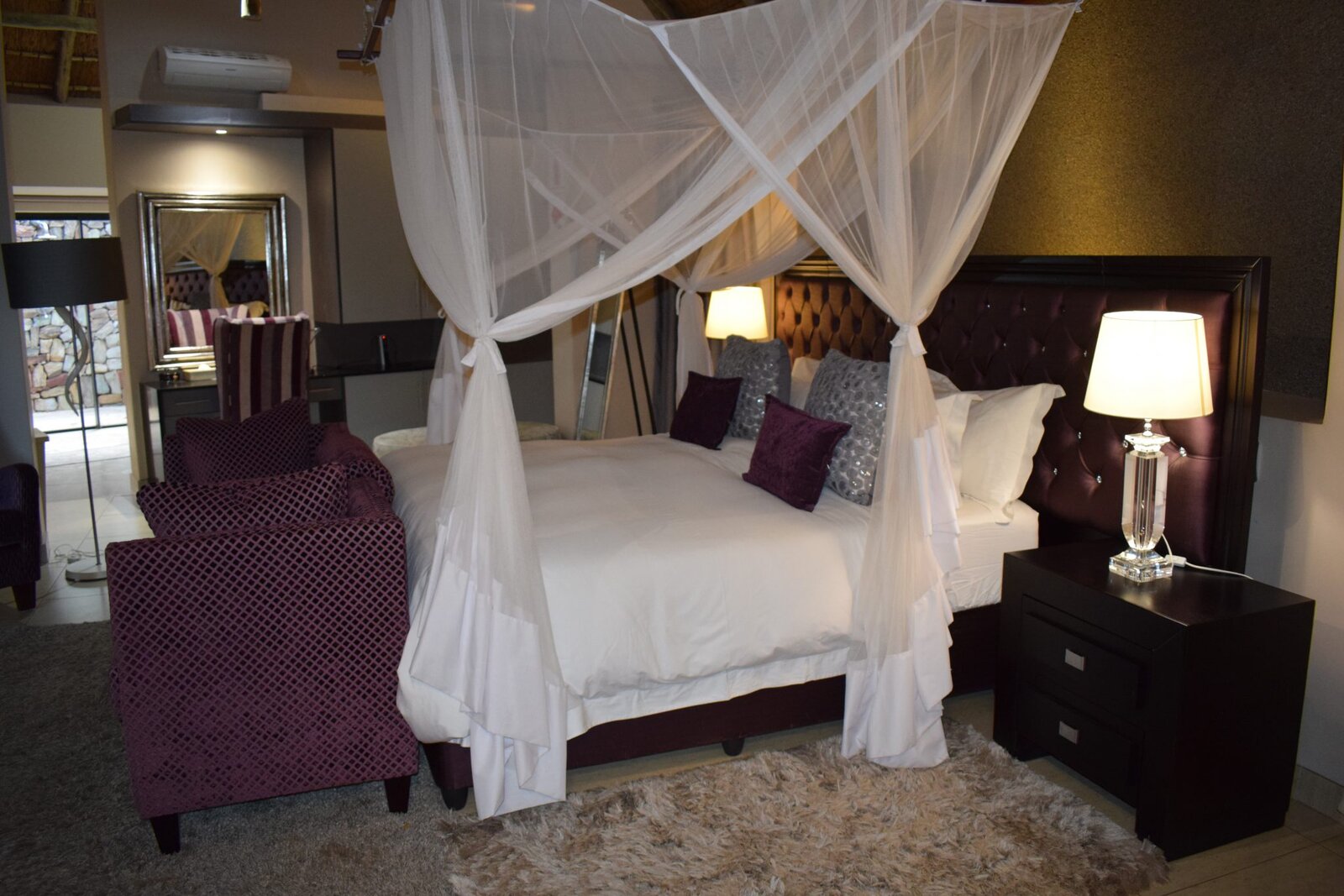 A four-poster canopy bed with drapes in a luxury suite at AM Lodge, Klaserie