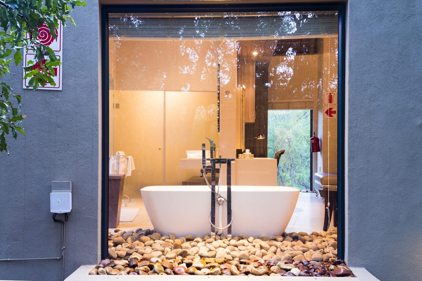 A freestanding tub beside a glass wall to an outdoor shower at AM Lodge, Klaserie