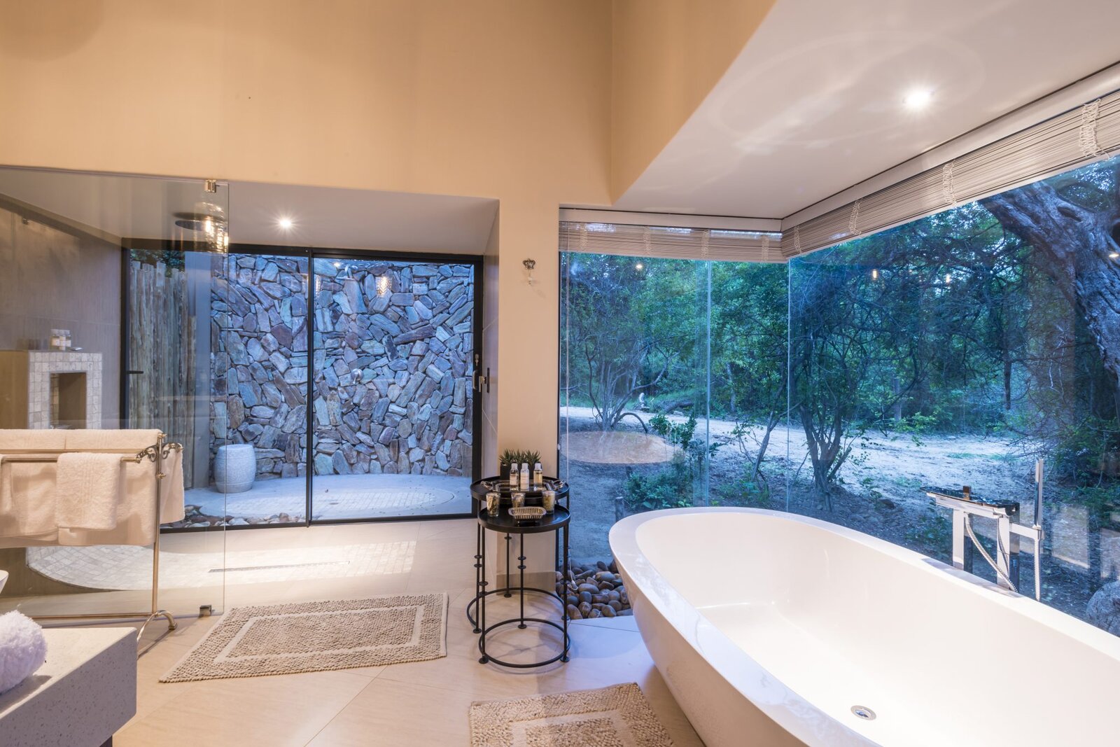 A bedroom and bathroom opening onto a private deck under thatch at AM Lodge, Klaserie