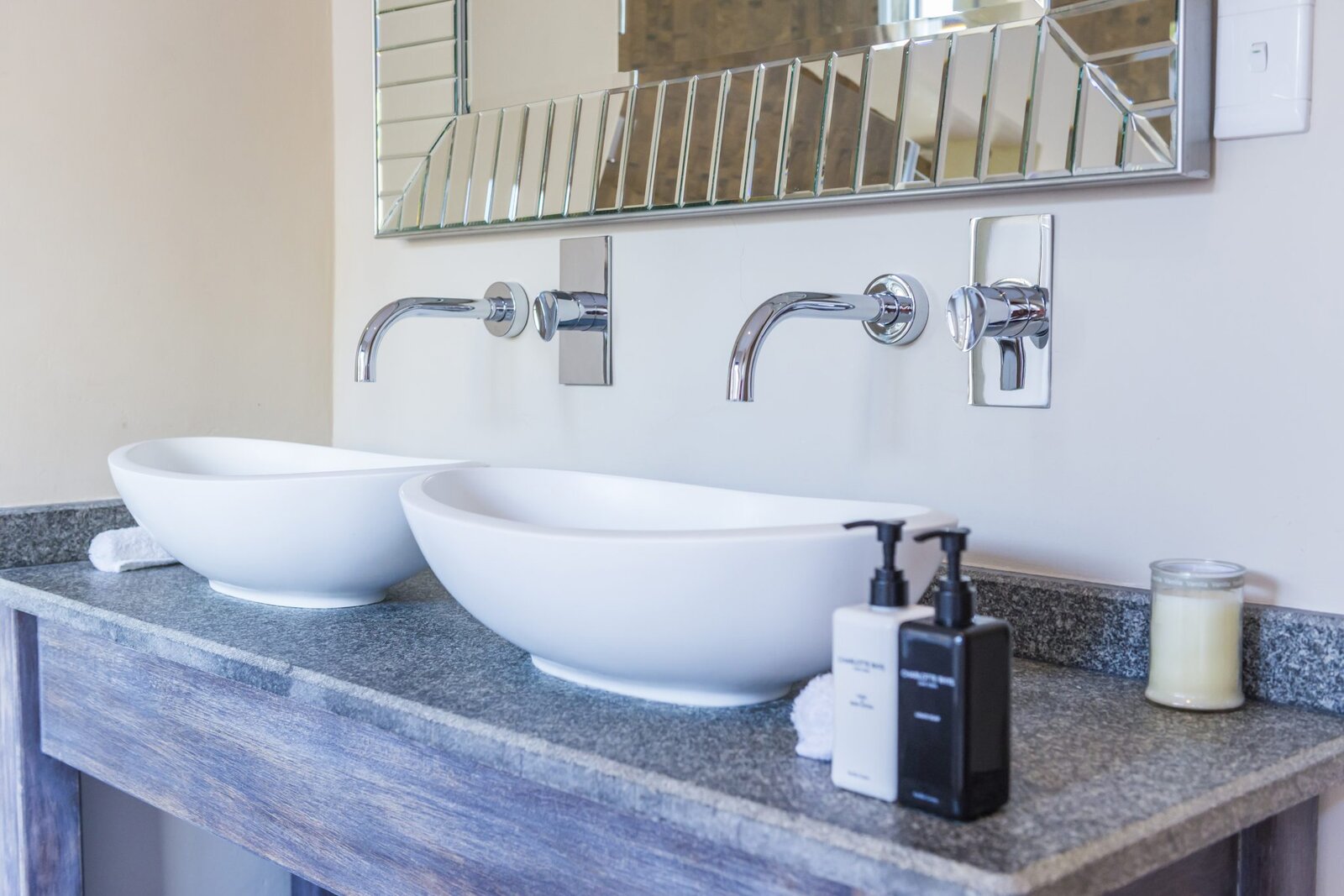 Twin white vessel basins on a stone vanity with a bevelled mirror in a suite bathroom at AM Lodge