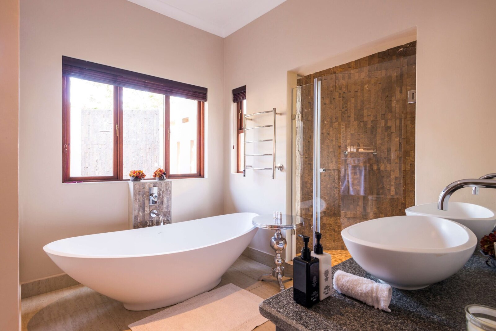 A freestanding bath and twin vessel basins in a light-filled suite bathroom at AM Lodge, Greater Kruger