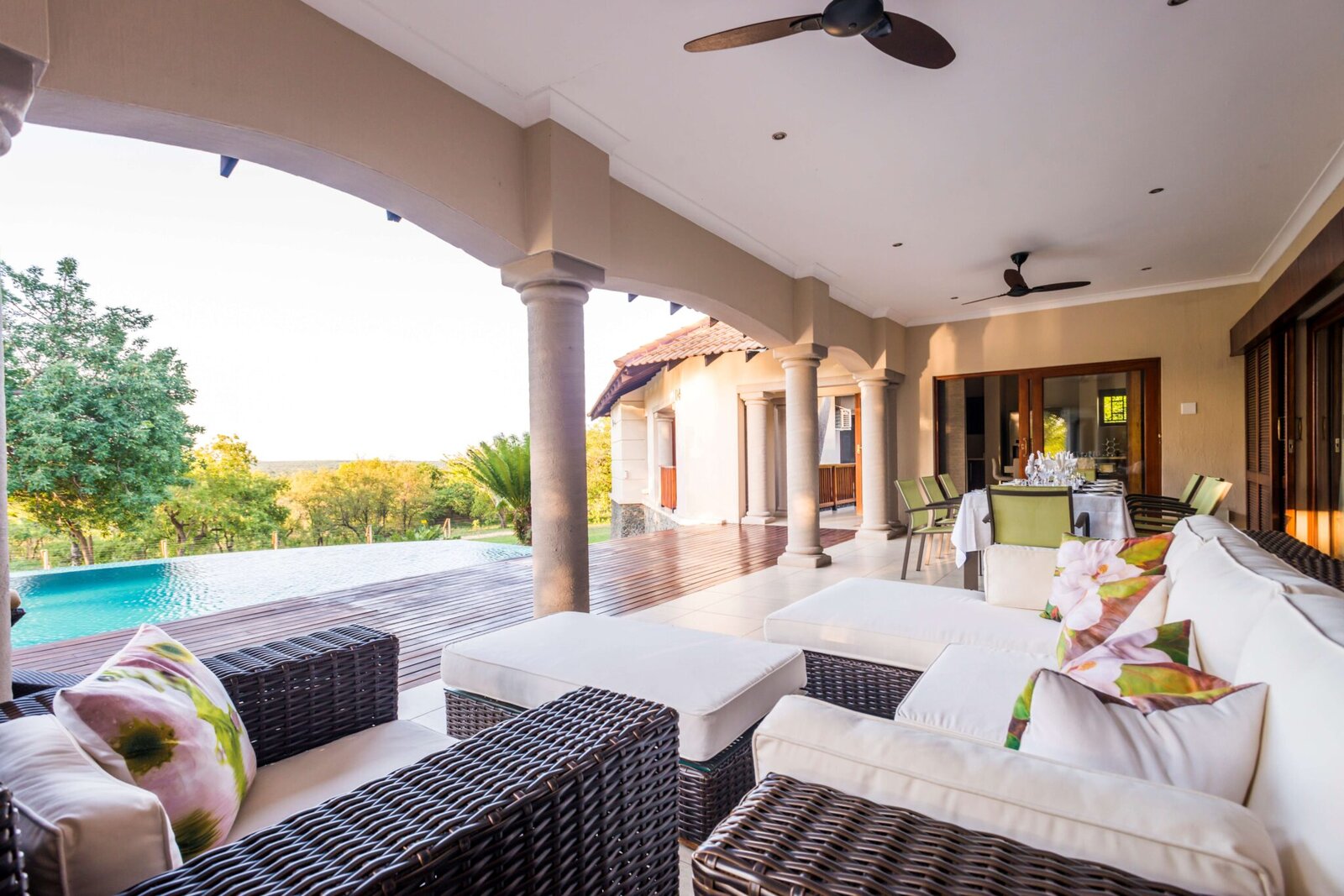 A covered terrace lounge overlooking the pool and bush at AM Lodge, Hoedspruit