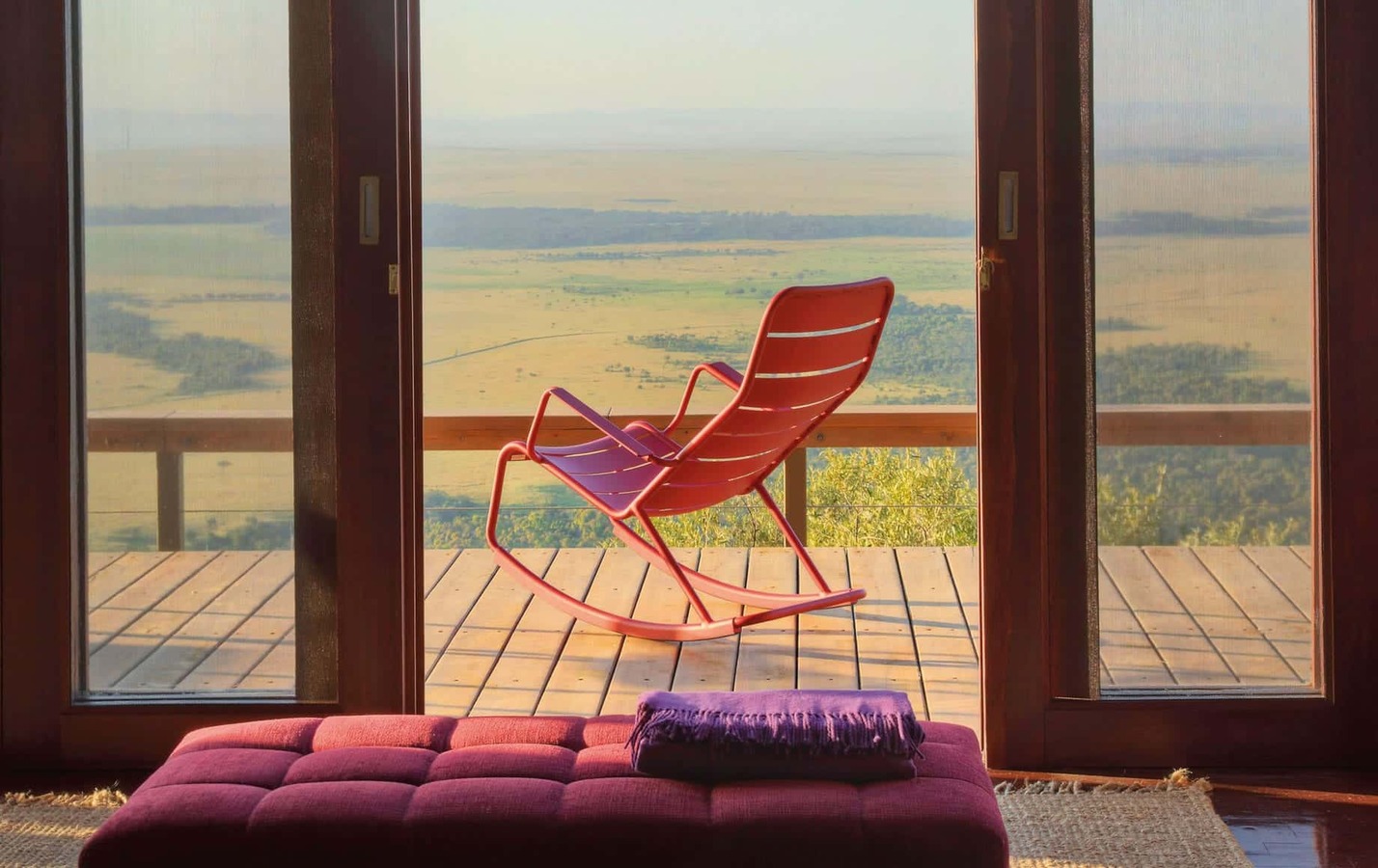 Angama Mara tented suite bedroom with king bed and floor-to-ceiling Mara views
