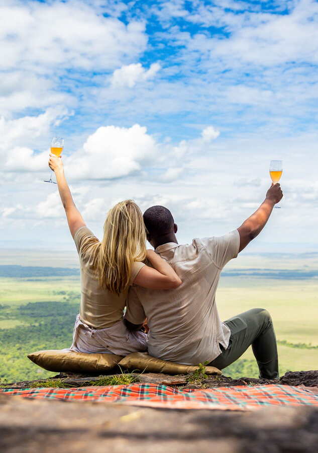 Out of Africa kopje picnic setup with white linen and champagne Angama Mara