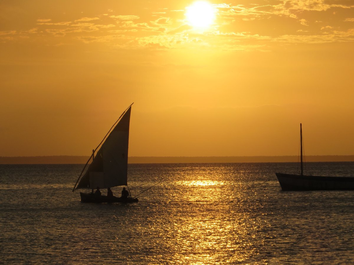 A traditional dhow sailing across a Bazaruto lagoon at sunset