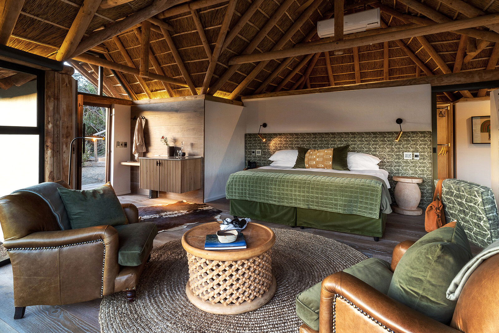 A king-size bed in a glass-fronted chalet at Kwandwe Great Fish River Lodge