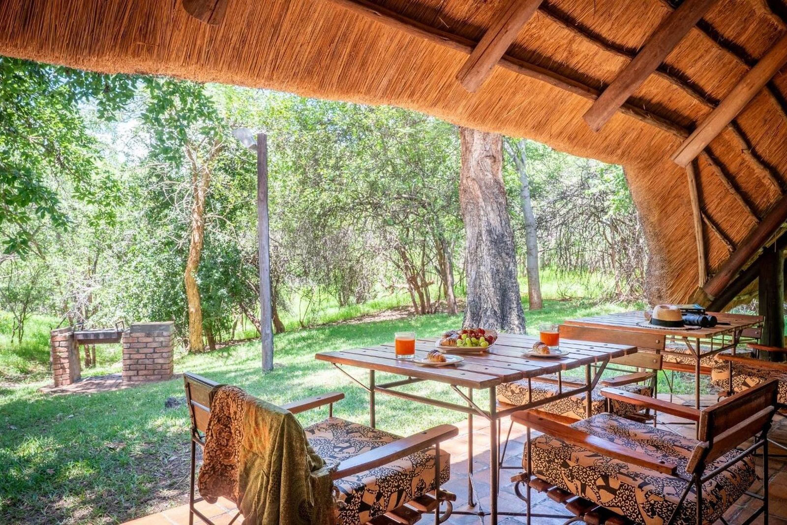 Thatched braai porch and private garden at a Lokuthula self-catering lodge in Victoria Falls