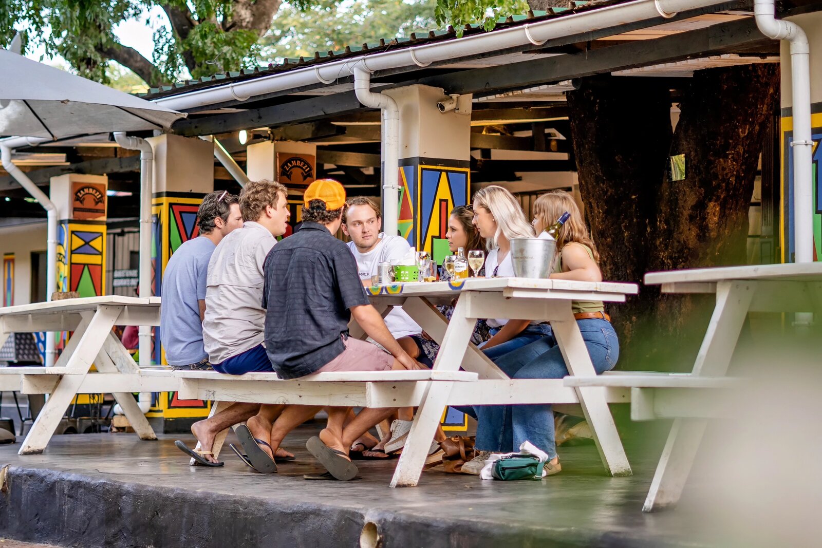 Travellers socialising at the outdoor bar and dining area of Shoestrings Backpackers, Victoria Falls