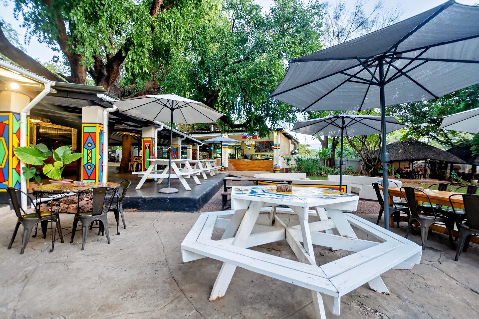 Shaded courtyard with picnic tables and umbrellas at Shoestrings Backpackers, Victoria Falls