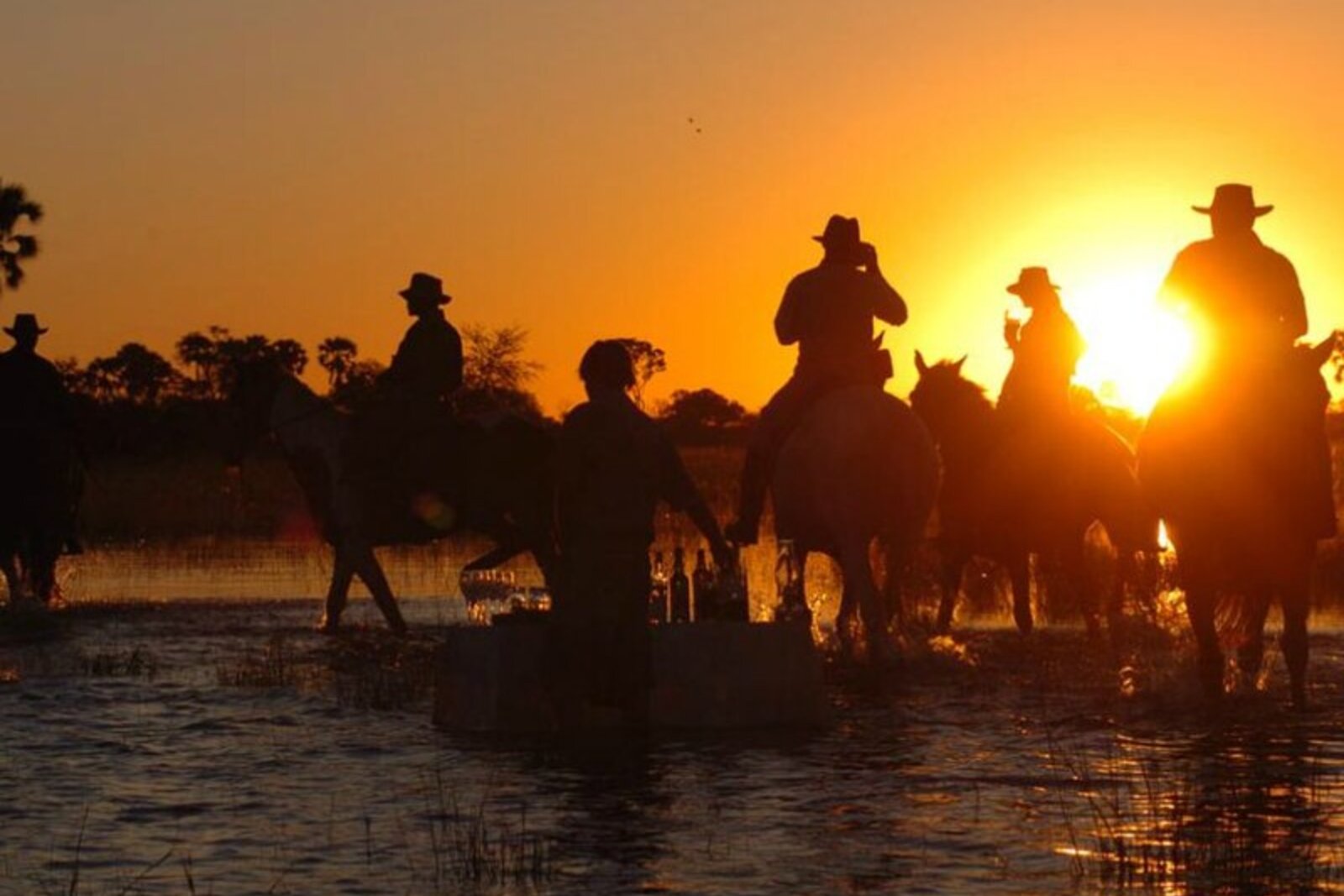 Big Five riders silhouetted at golden hour on a mobile horseback trail near Kruger