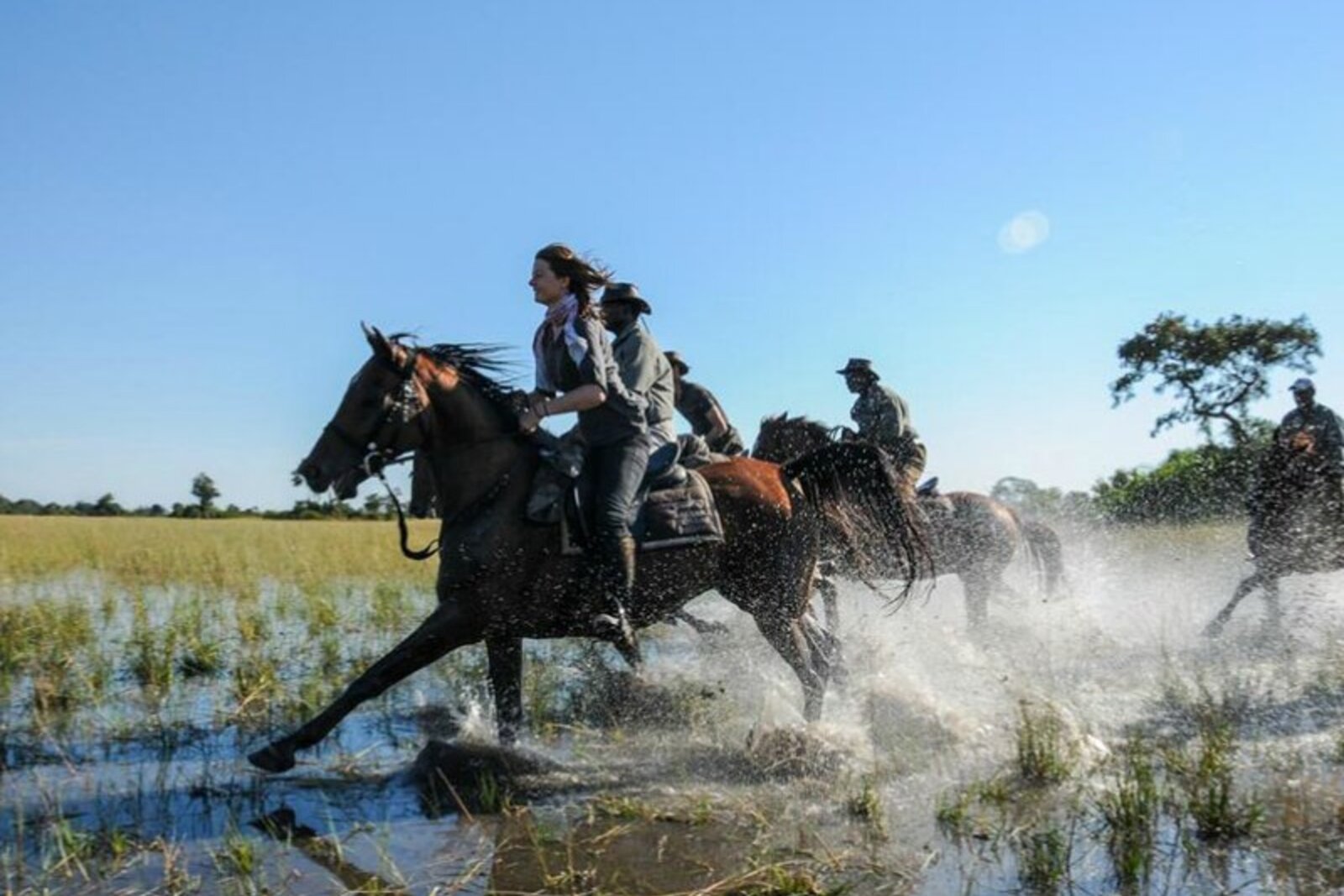 A rider cantering through a lowveld waterhole on a Big Five horseback safari