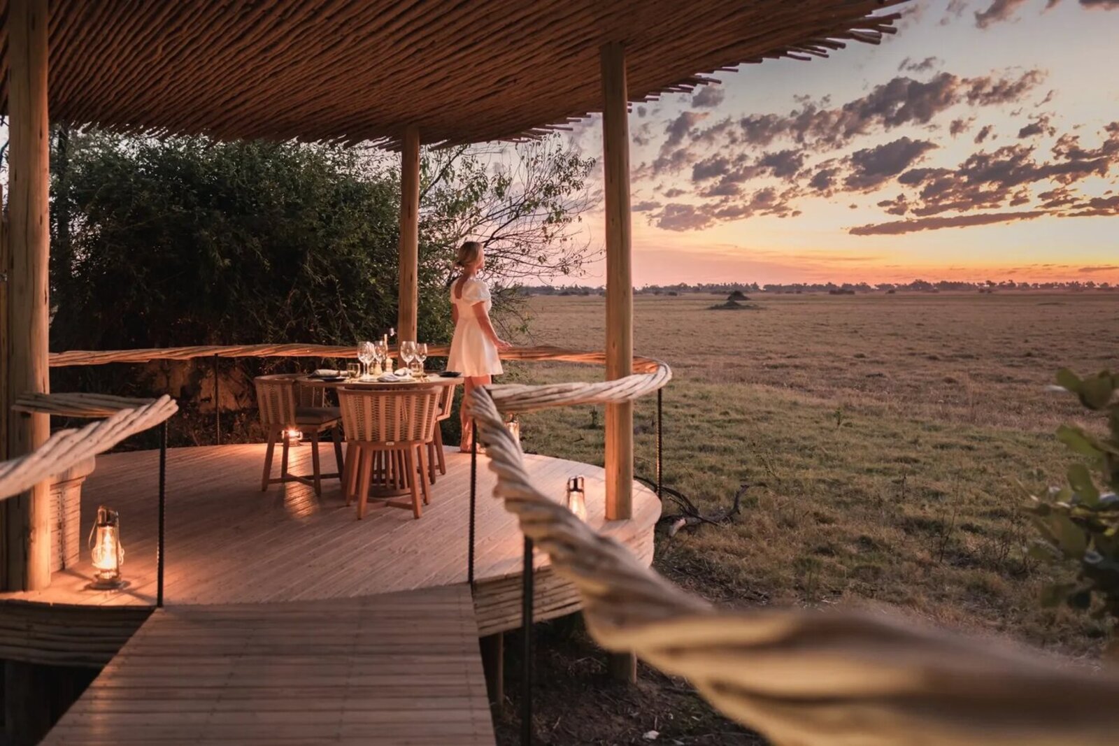 A private candlelit dinner set for two on a deck at sunset on a luxury couples safari