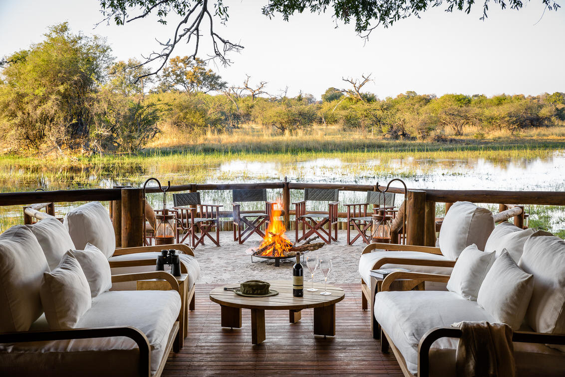 A raised lounge deck with fire pit over the water at Sanctuary Chief's Camp in the Okavango
