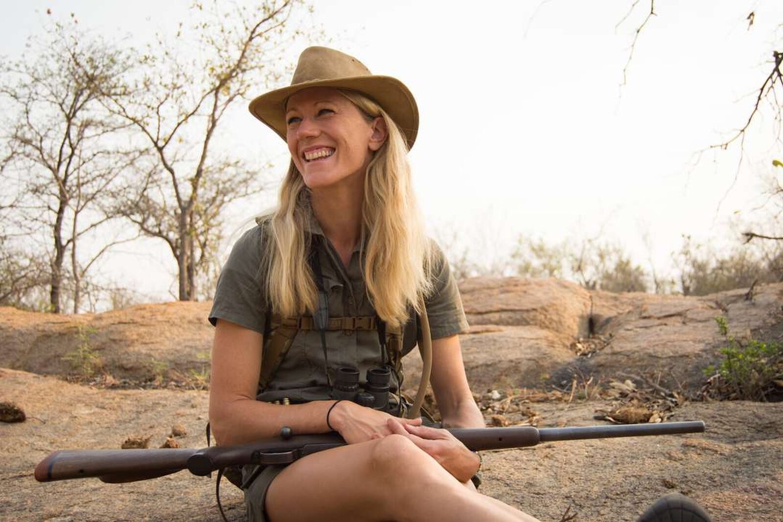 Expert safari guide tracking wildlife with private guests in an open game drive vehicle