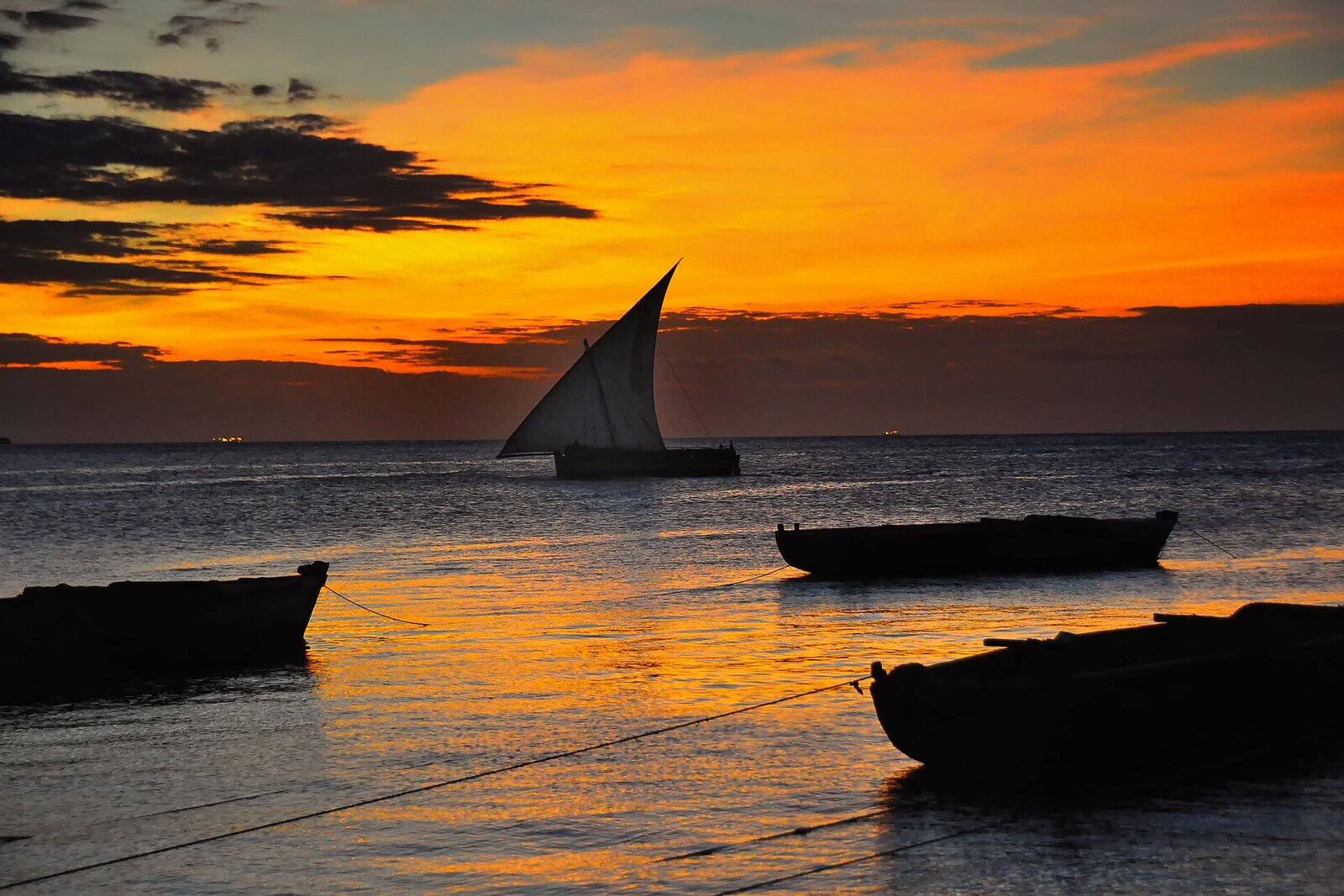 A traditional dhow sailing at sunset off Zanzibar &mdash; the dry season is the best time to visit the spice island