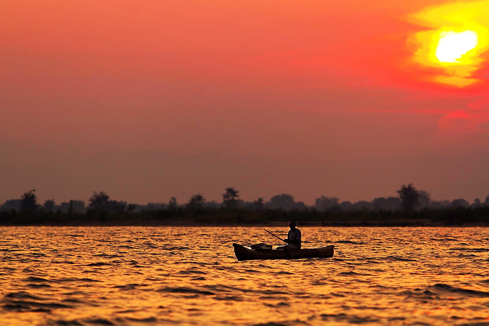 A lone canoe silhouetted against a fiery Lake Malawi sunset