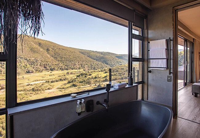 En-suite bathroom with copper bath and mountain views at Botlierskop Tented Lodge