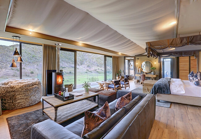 Botlierskop Tented Lodge suite bedroom with four-poster bed and mountain views
