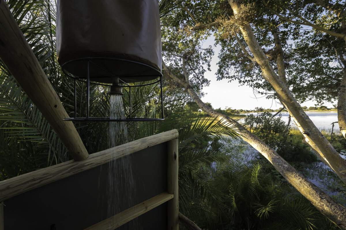 En-suite bush bathroom with hot-water bucket shower at a mobile camp