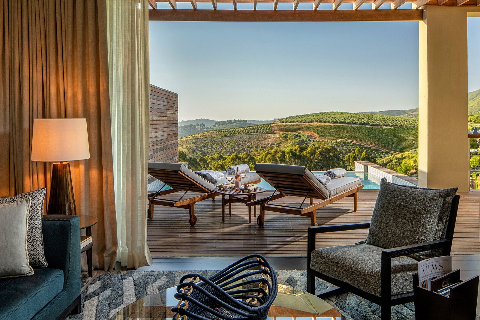 Opulent hotel suite with four-poster bed, chandelier and vineyard views