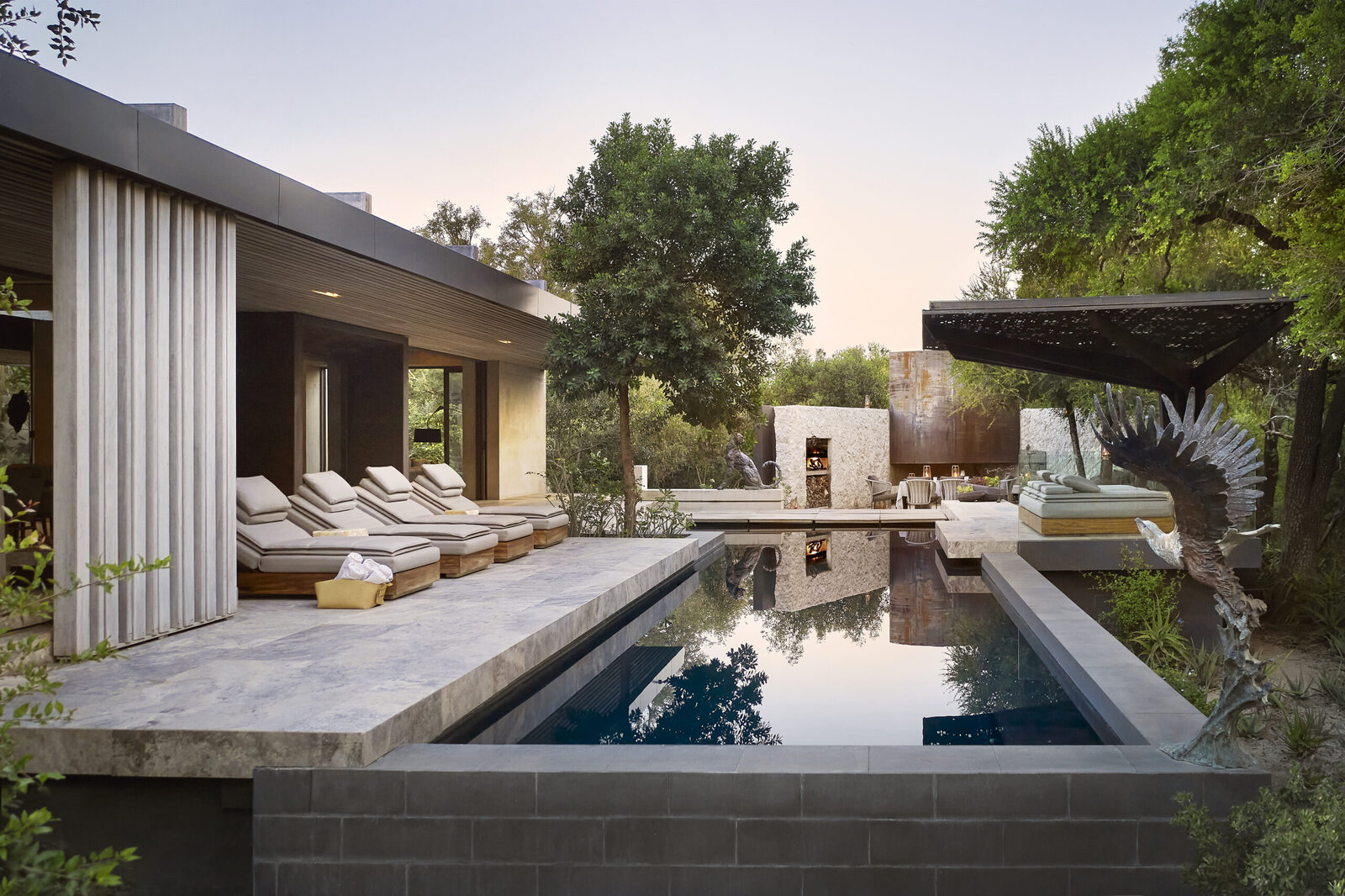 The pool deck and contemporary architecture of a Cheetah Plains Plains House, with loungers beside the water