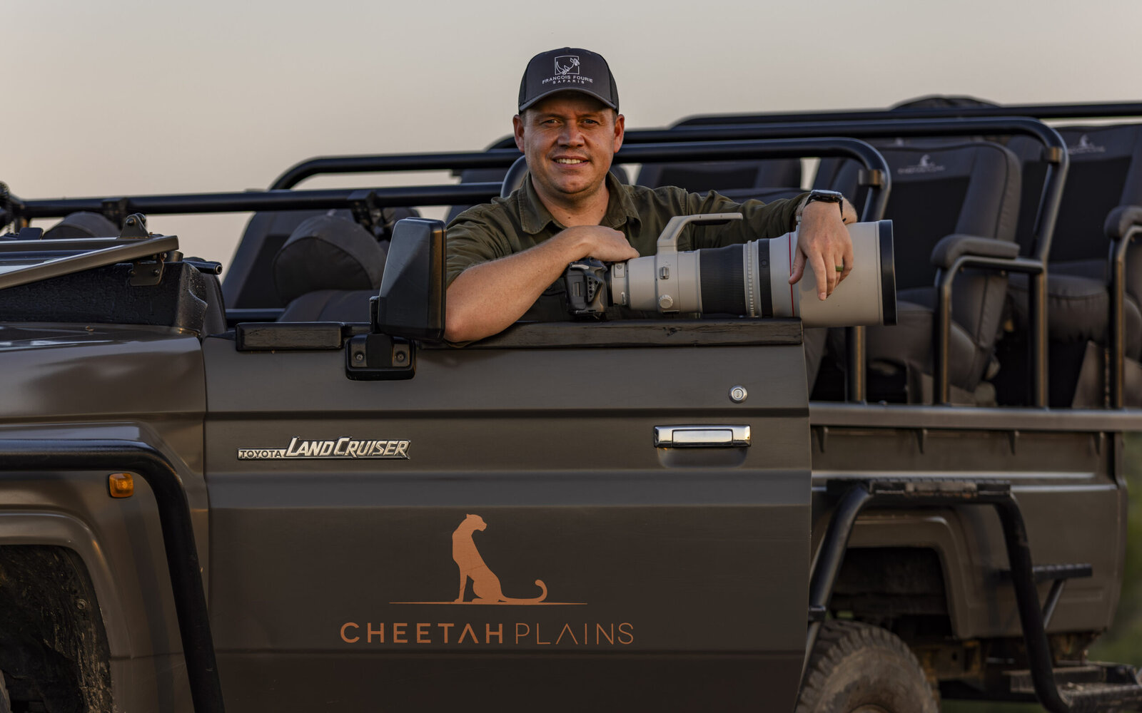 A branded Cheetah Plains electric Land Cruiser game-drive vehicle with a guide, in the Sabi Sand bush
