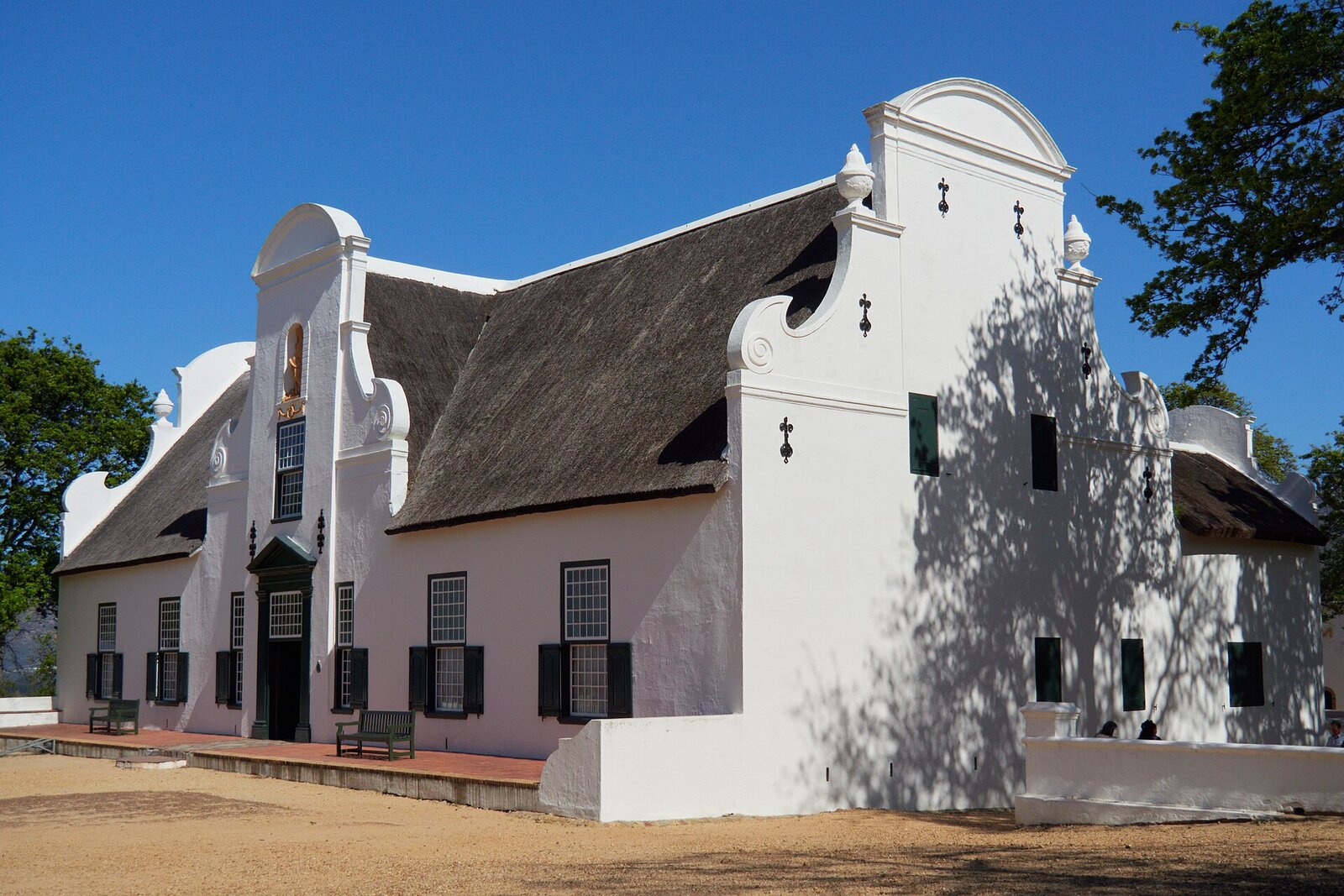 Whitewashed Cape Dutch manor house with gabled facade among vineyards