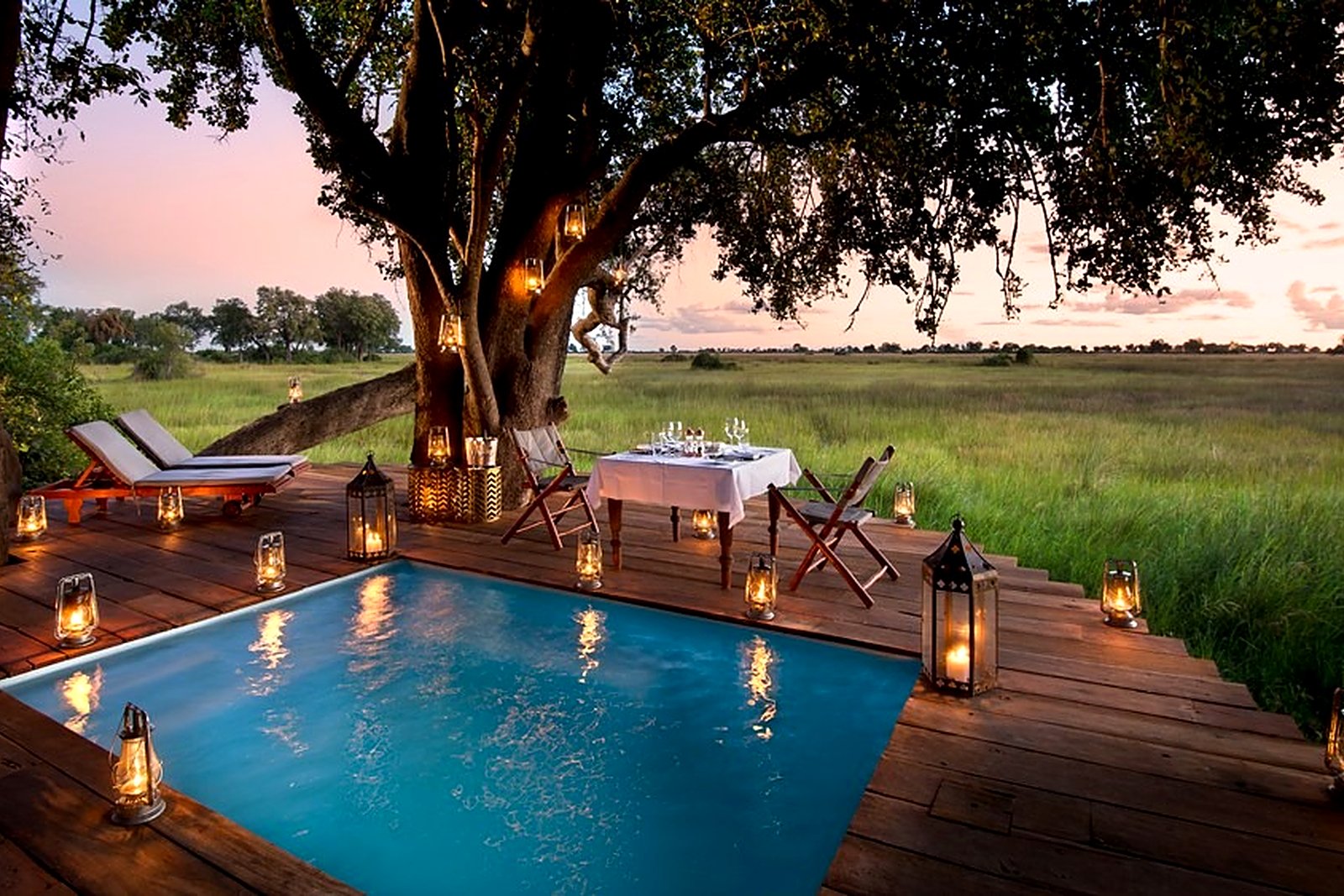 Lantern-lit plunge pool on a raised deck at Duba Plains Camp at dusk