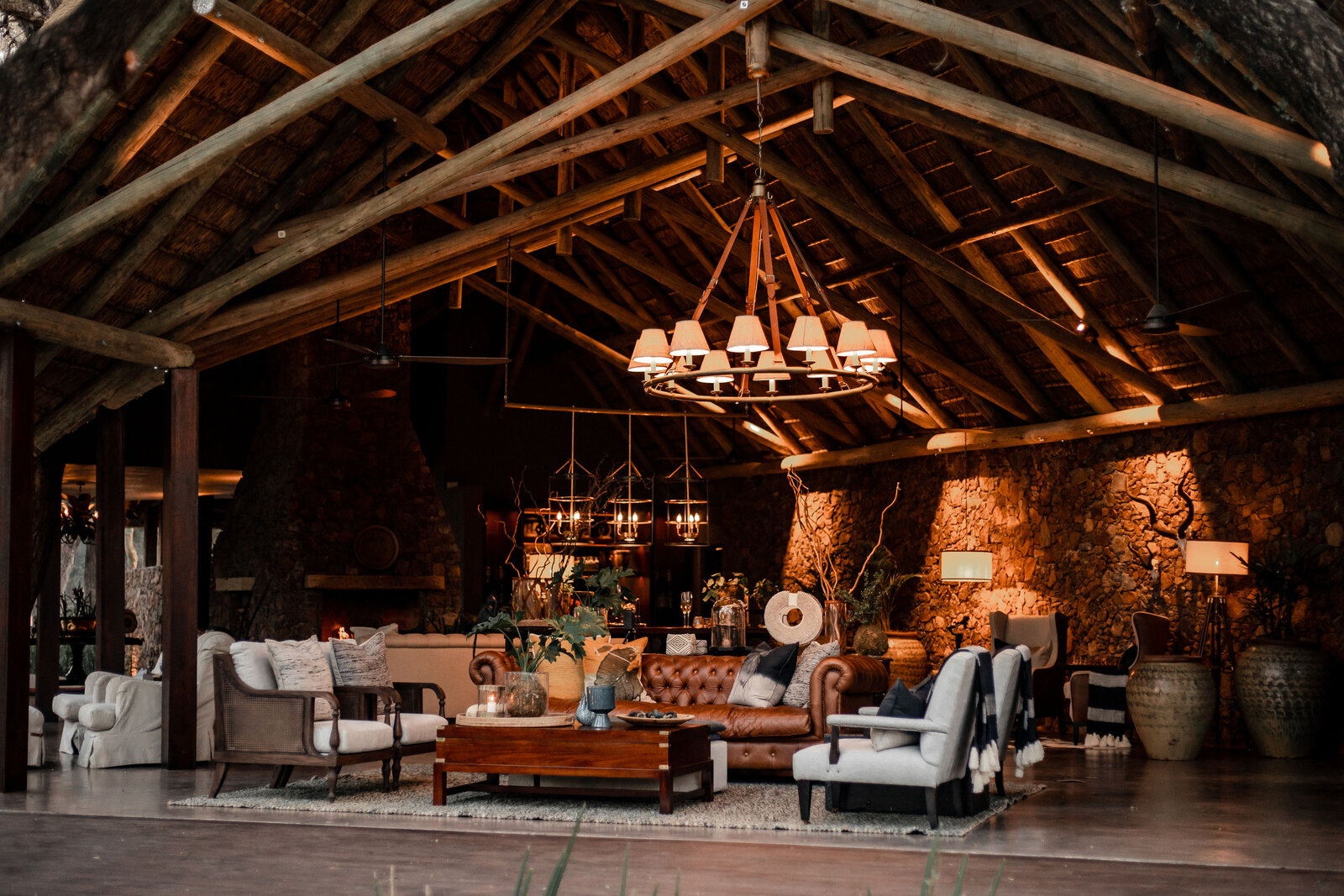 Dulini main lodge lounge with stone walls, African art, chandeliers and warm firelight