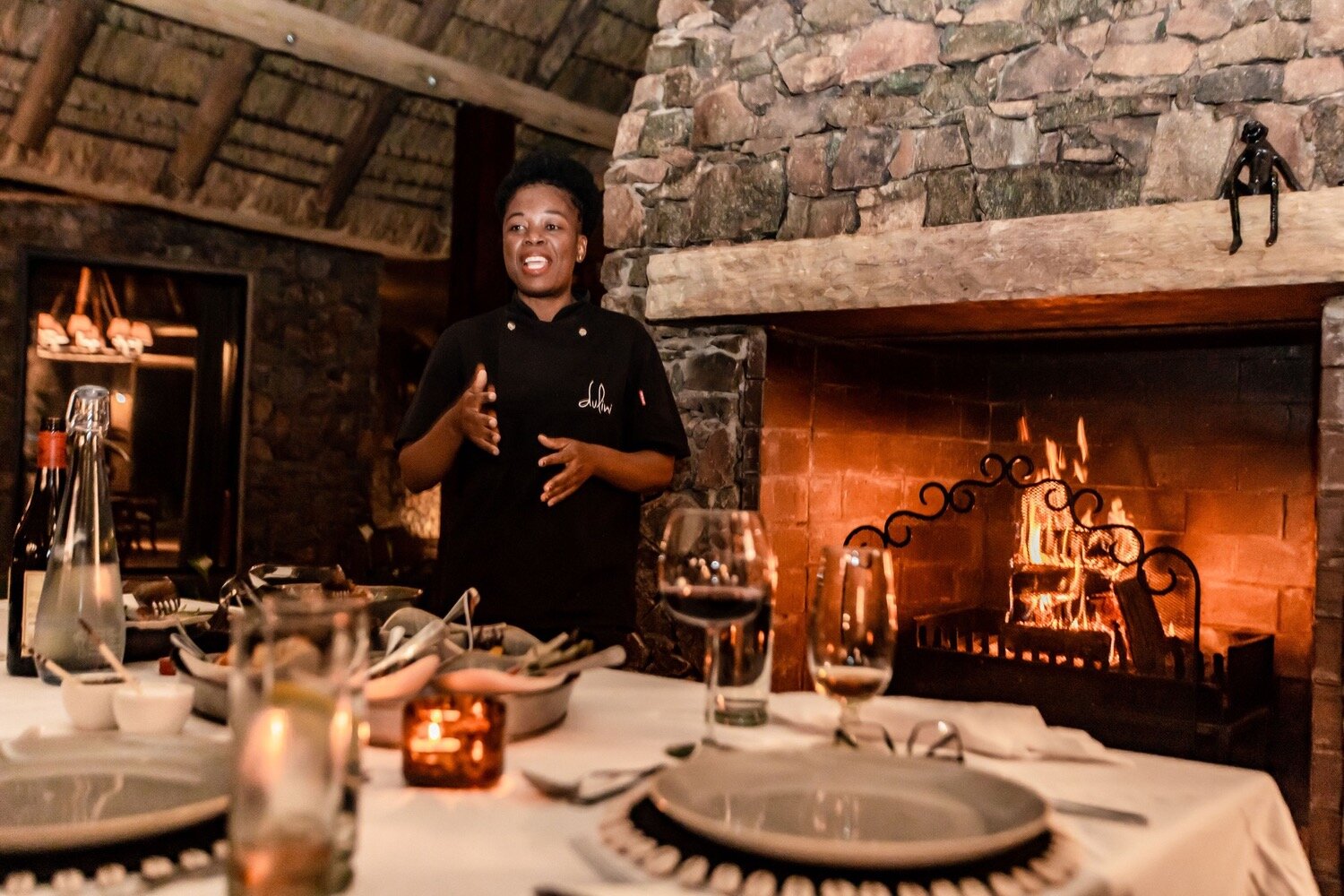 Candlelit dinner table set in the stone boma at Dulini with fireplace