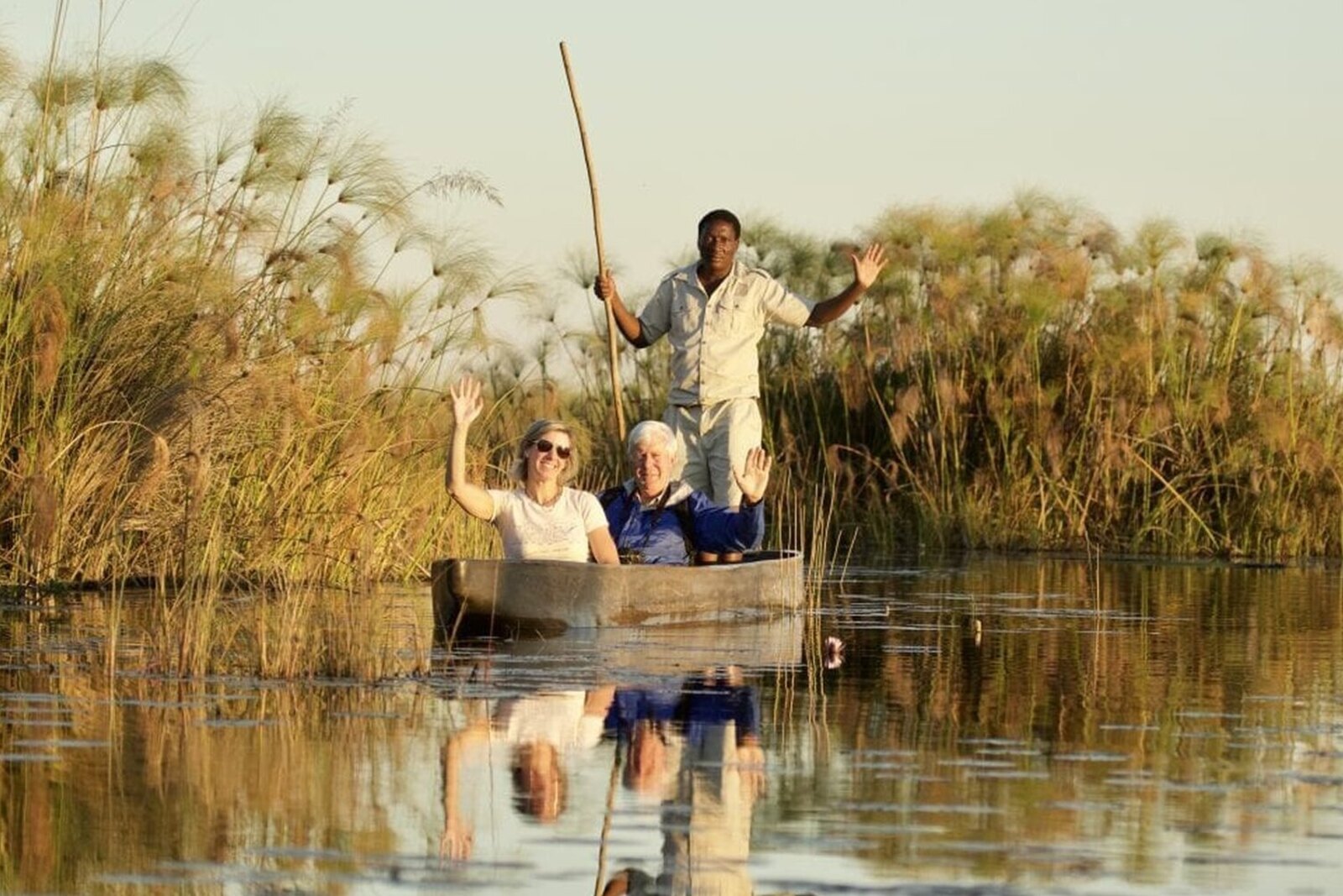 A family gliding through the Okavango Delta in a mokoro on an African safari family package