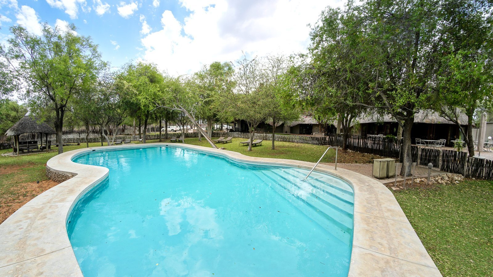 Mushara Lodge pool and garden with Etosha scrubland behind