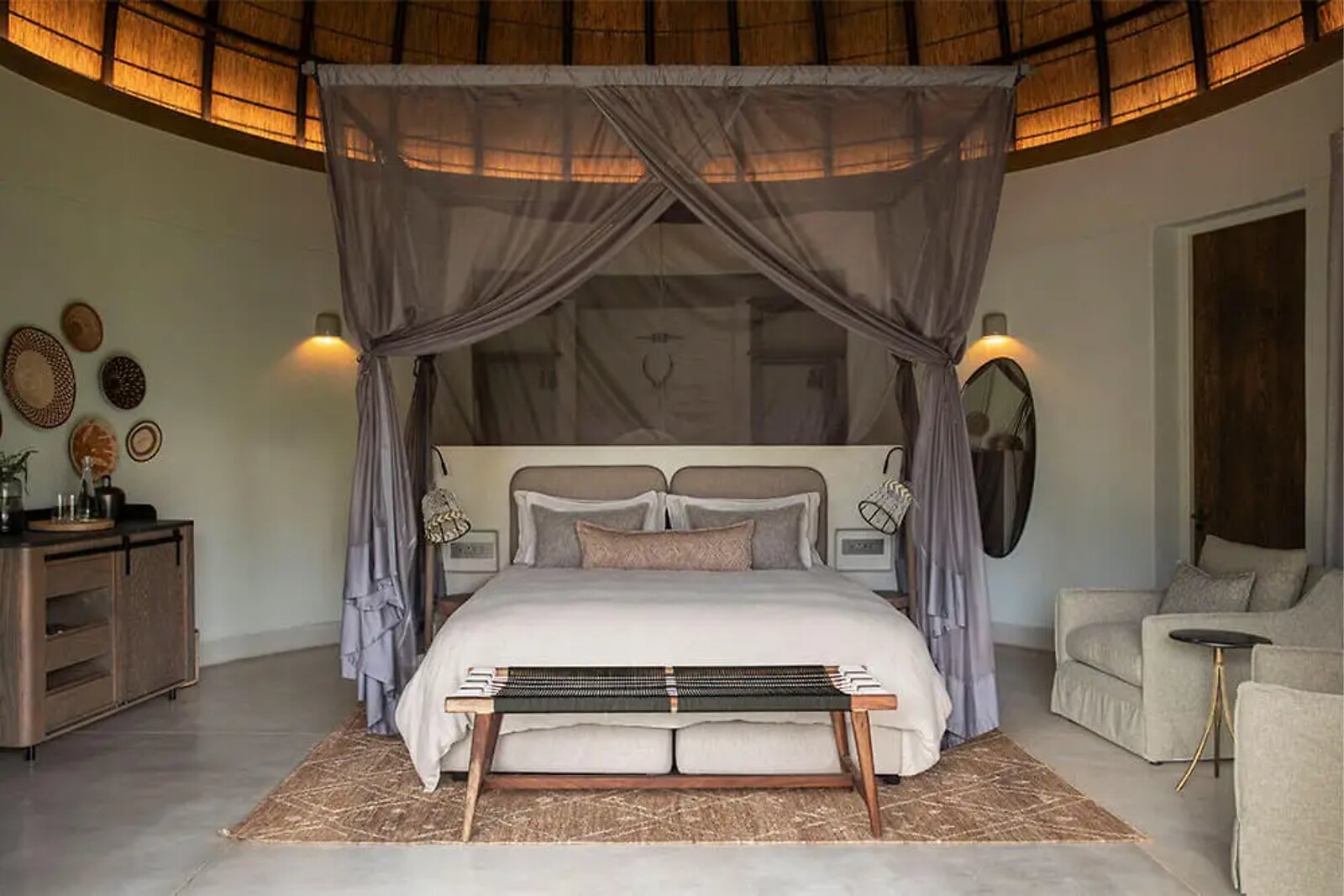 Draped king bed with dressing area inside a dome-shaped Indlu suite at Fifty-Five Mjejane