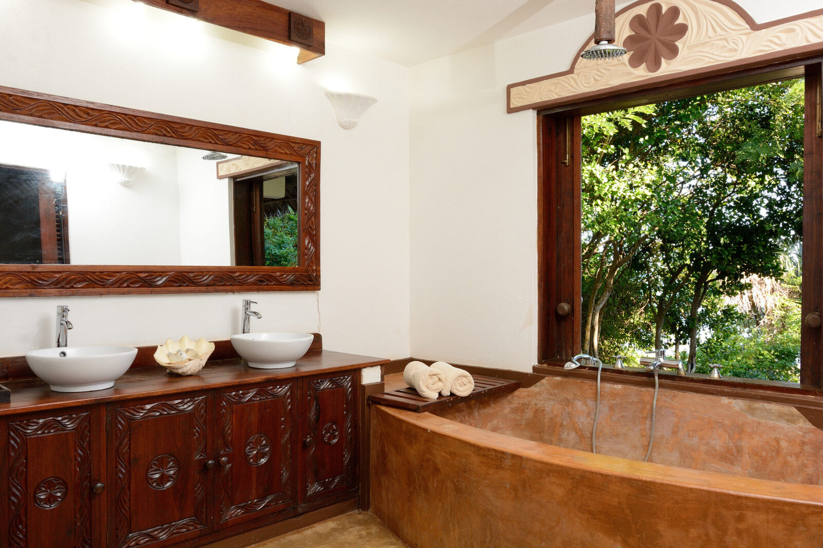 Suite bathroom with carved vanity, twin basins and a bathtub at Fumba Beach Lodge
